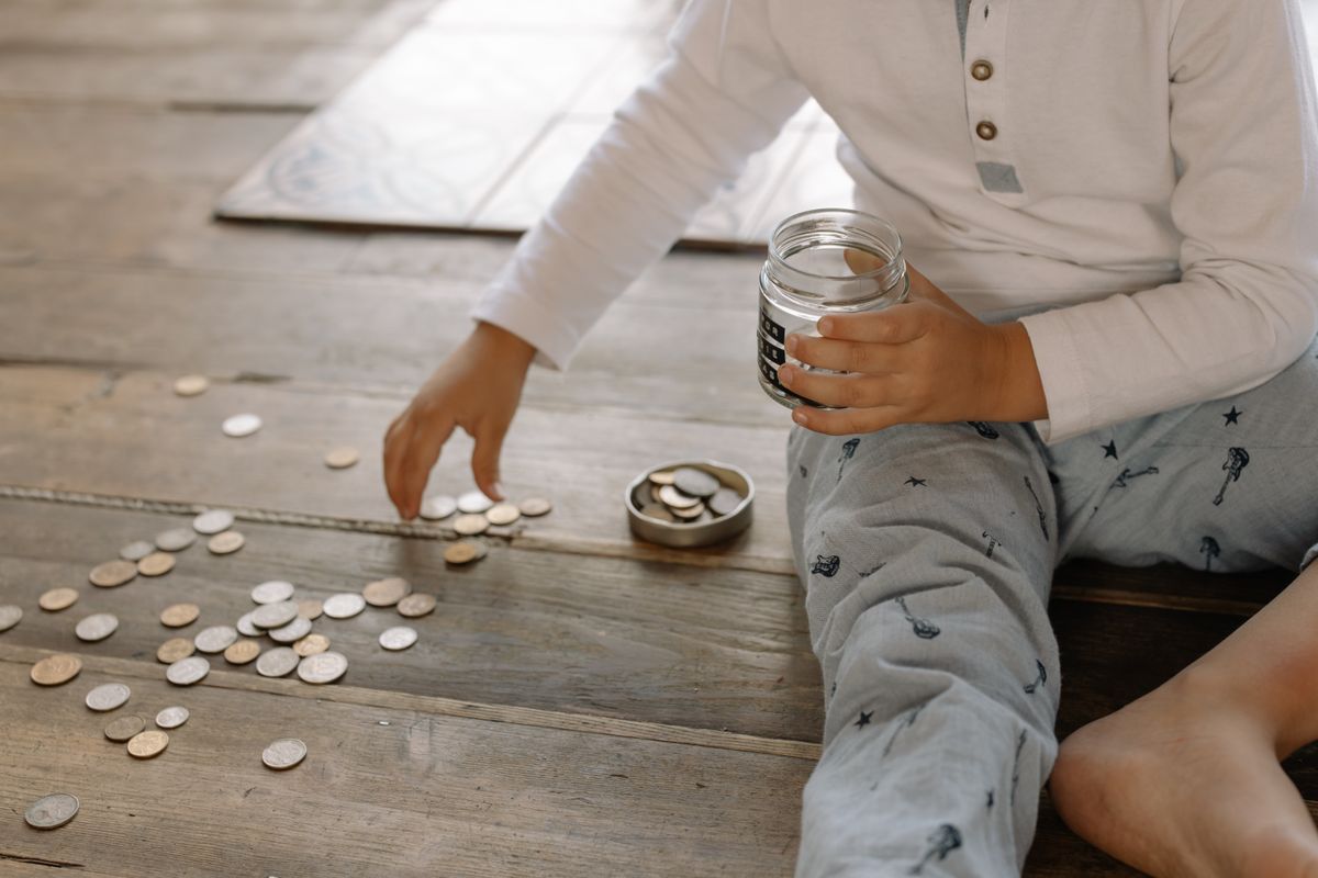 Child putting coins into a glass jar